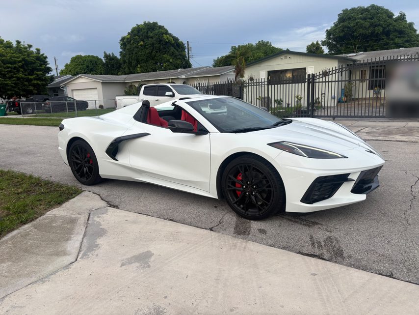White 2027 Chevrolet Corvette C8 with the roof down and red seats